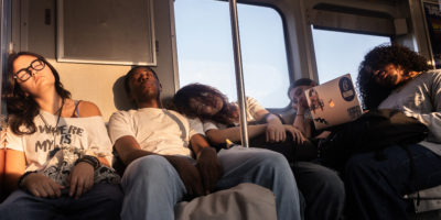 Students on the seats of the subway car sleeping.
