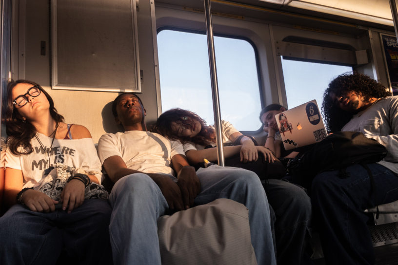 Students on the seats of the subway car sleeping.