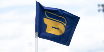 A blue flag with the yellow TMU Bold logo on it.