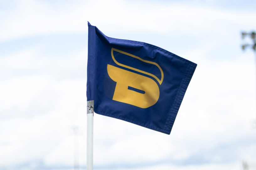 A blue flag with the yellow TMU Bold logo on it.