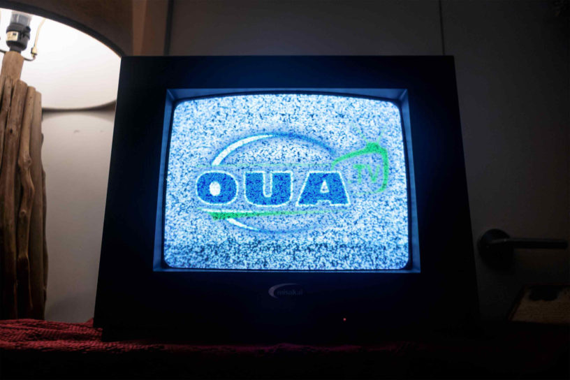 An image of an old television with a blue and grainy OUA logo on it.