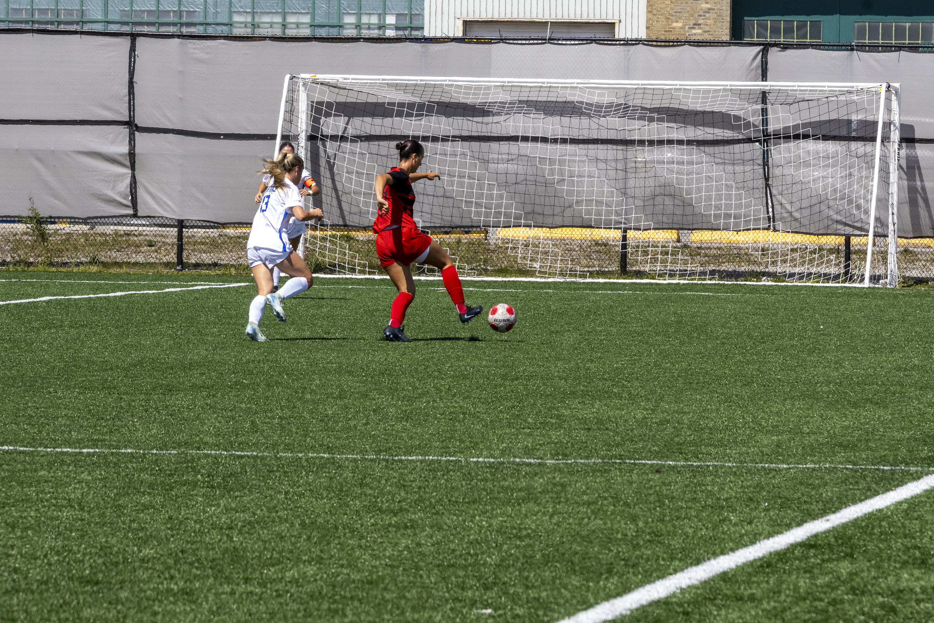 A soccer player manoeuvre a soccer ball towards the net