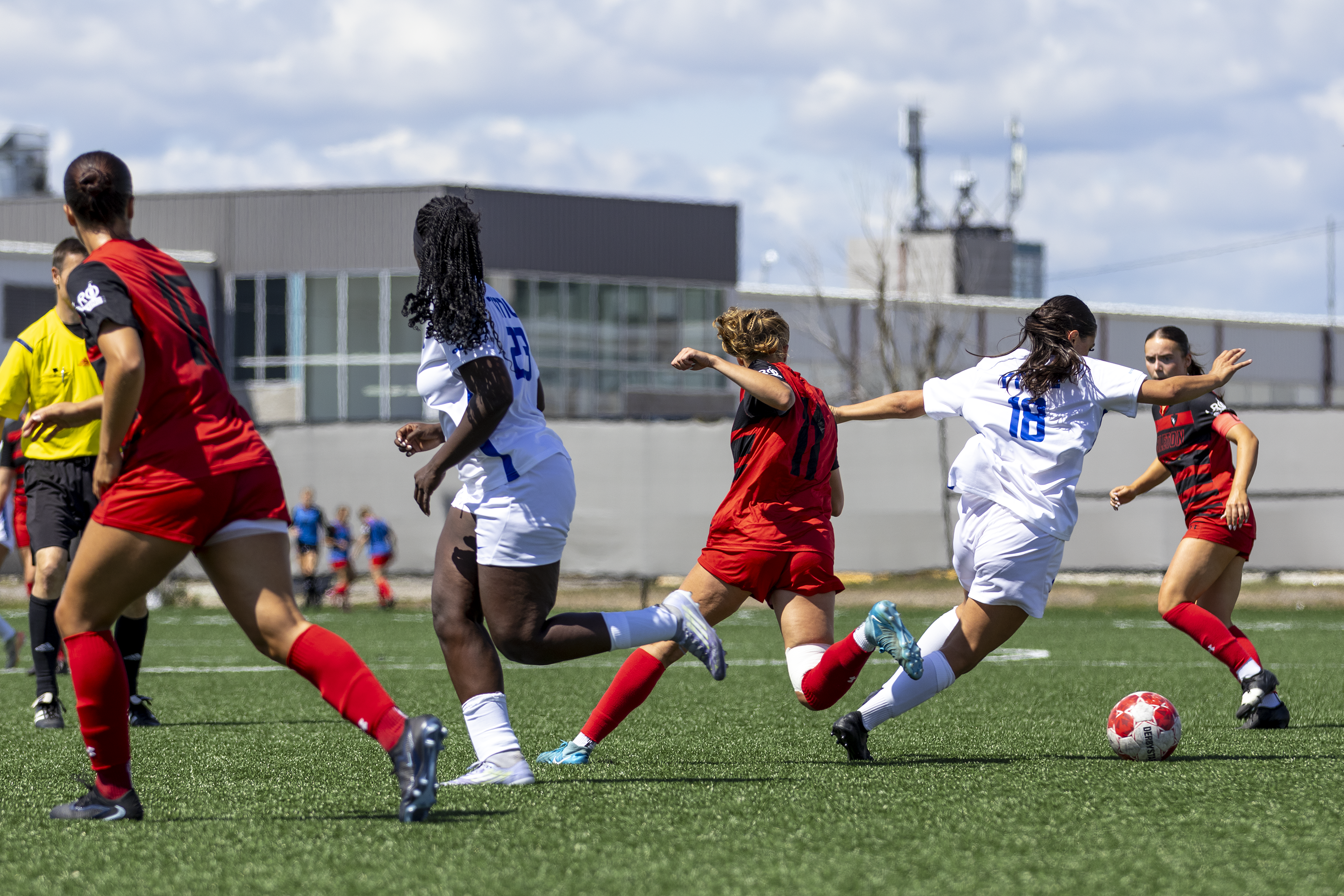 A soccer player weaves around her opponents to gain possession of the ball