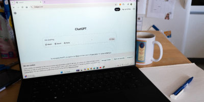Picture of black laptop on a desk with the AI website, “ChatGPT” open.