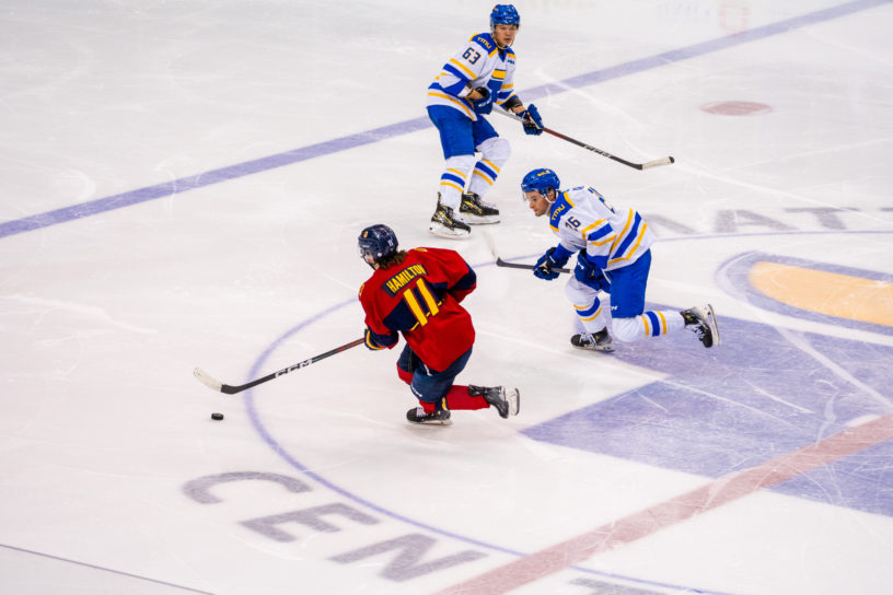 A Queen's player with the puck avoids his opponents