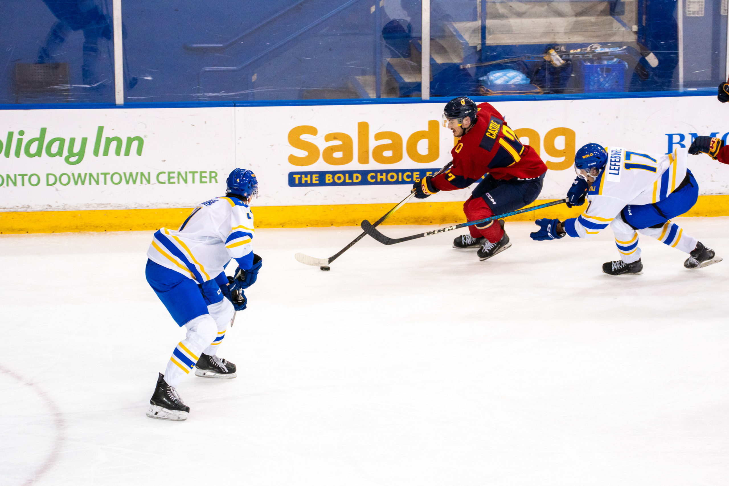A Queen's player with the puck weaves through his opponents