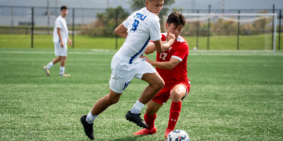 A TMU and RMC soccer player fight for possession