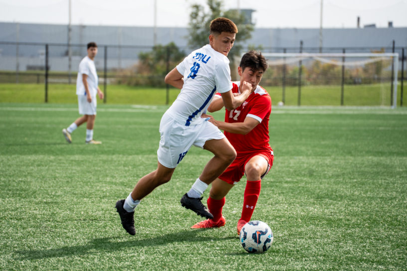 A TMU and RMC soccer player fight for possession
