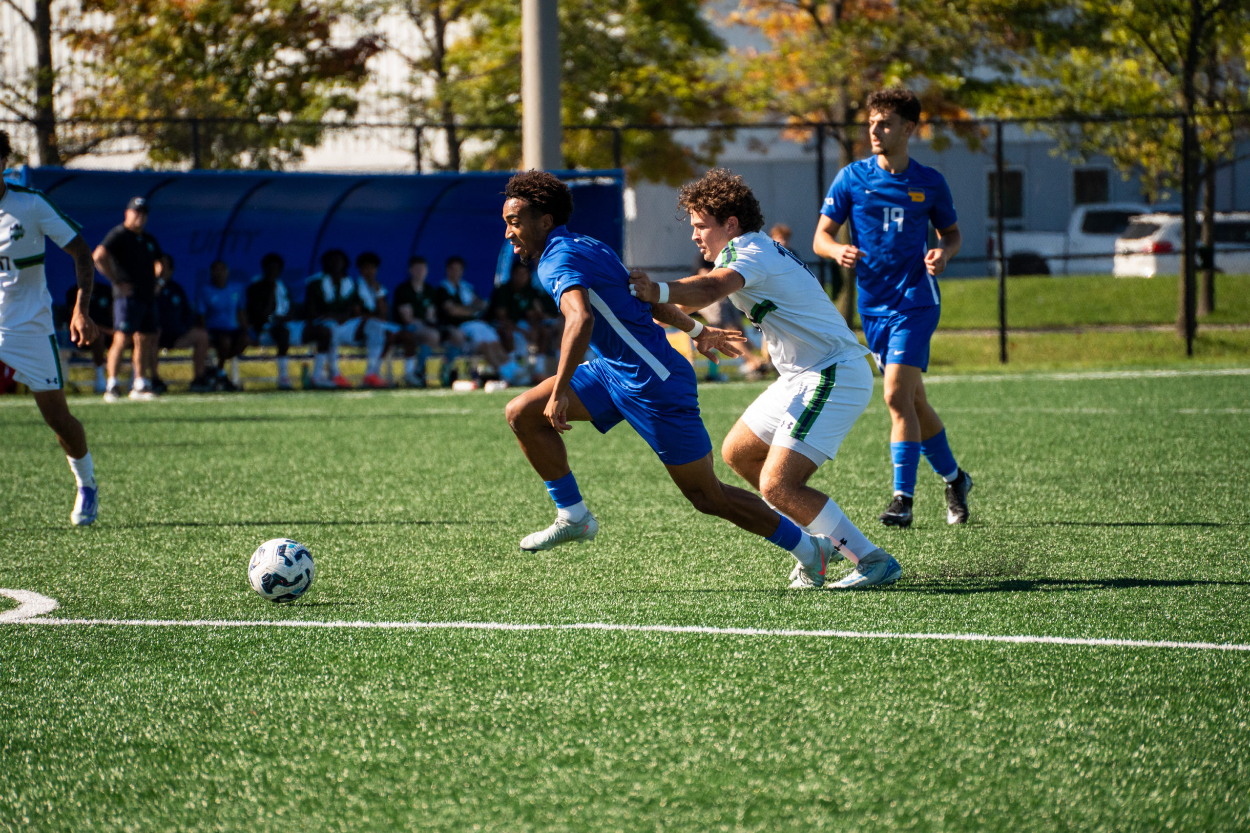 A TMU and Nipissing soccer player race for possession of the ball