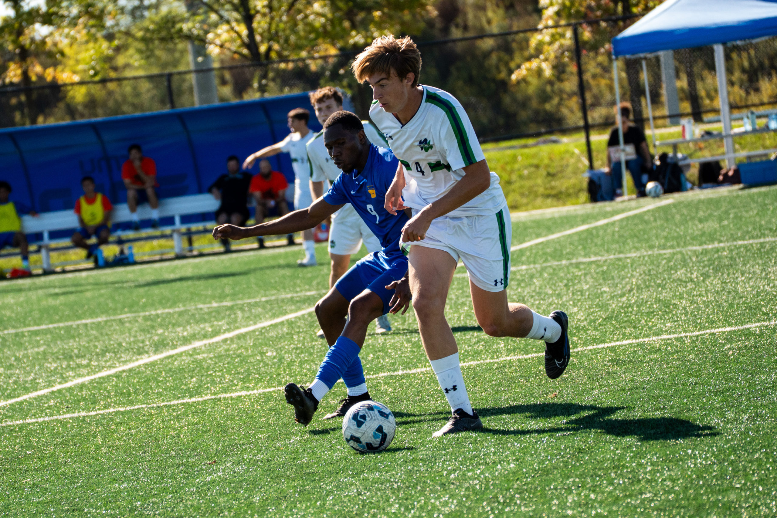 A TMU and Nipissing soccer player fight for possession of the ball