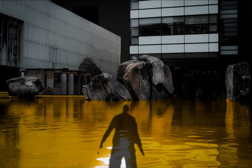 An photo illustration of a shadow of a person over a yellow coloured Lake Devo.