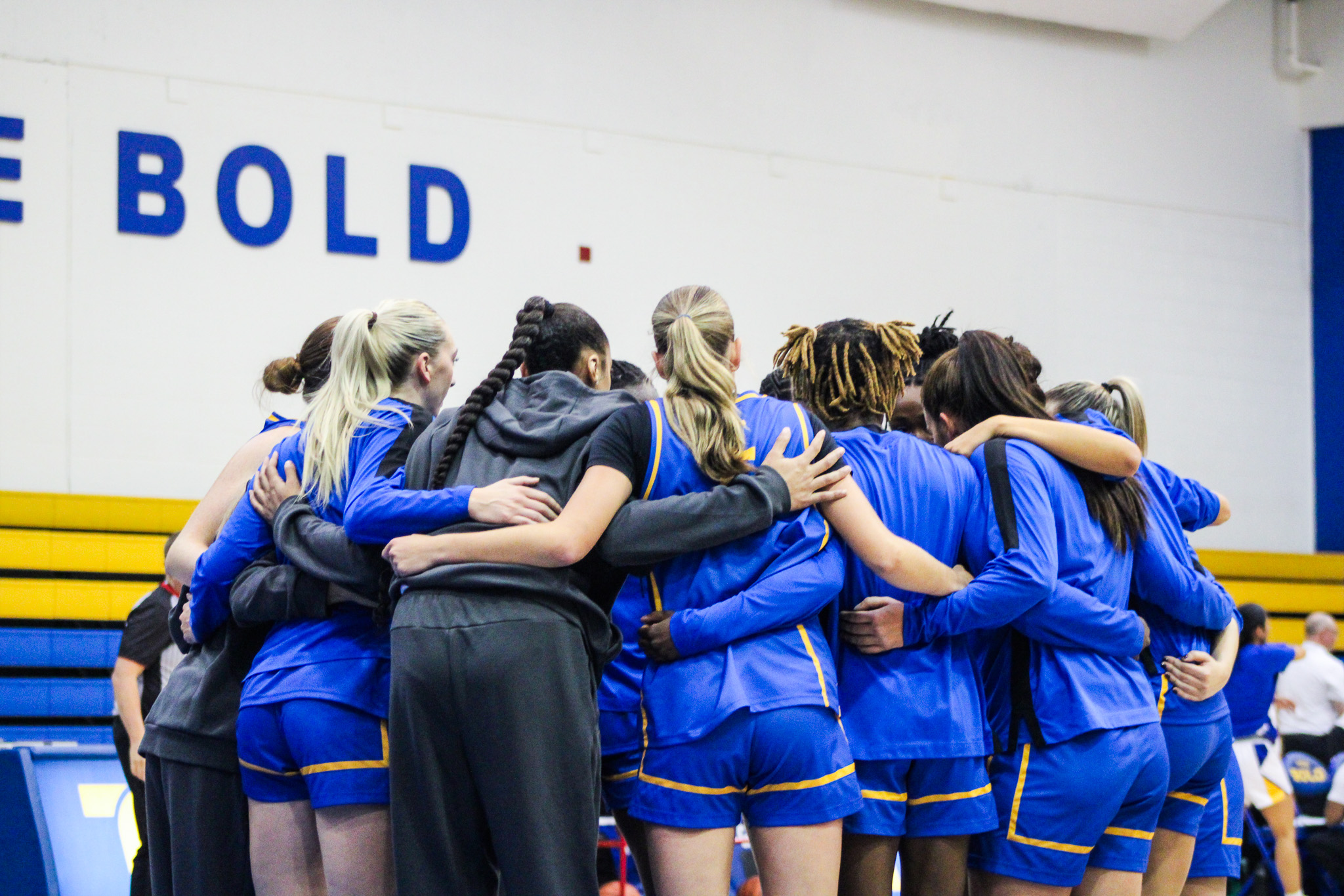 The TMU Bold women's basketball team huddle together