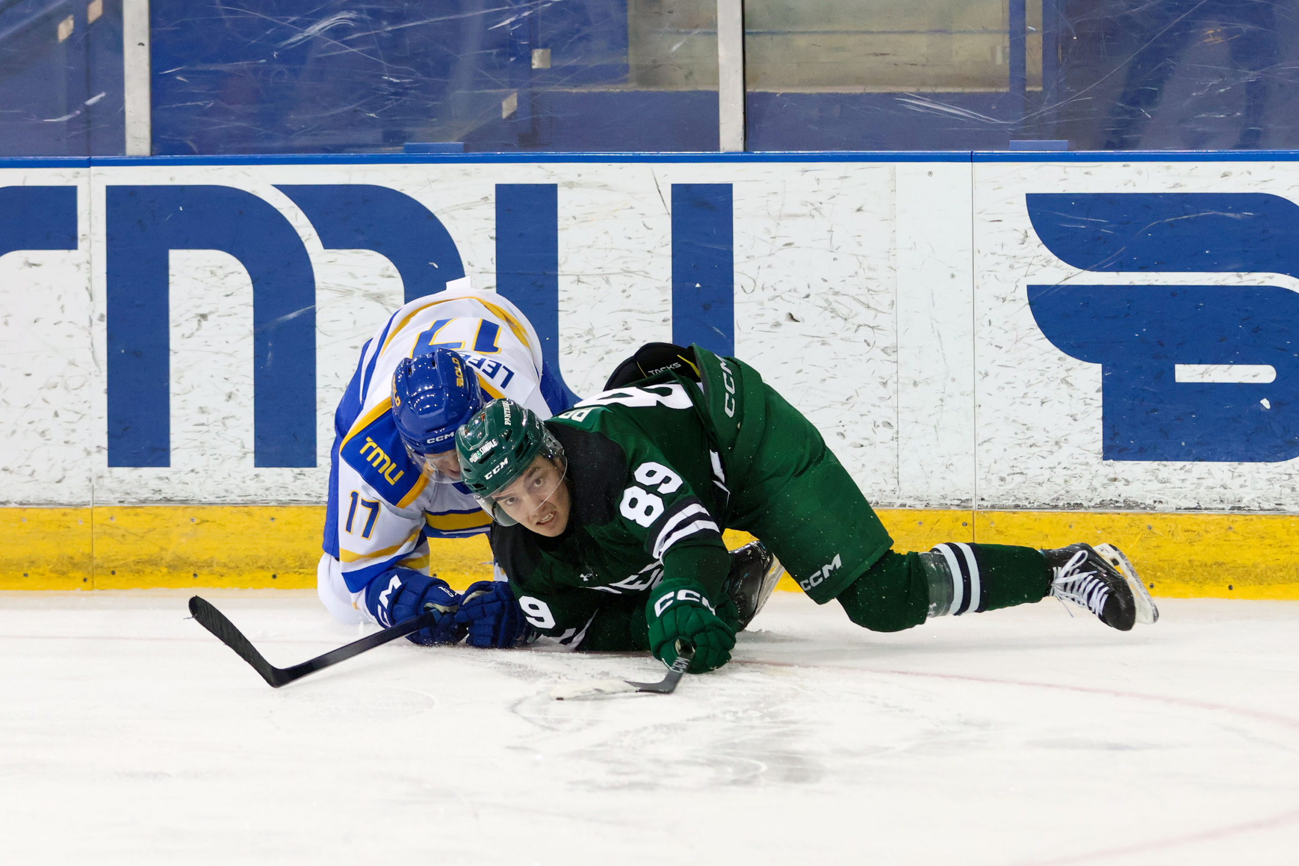 A TMU and UPEI player try to get up from the ice