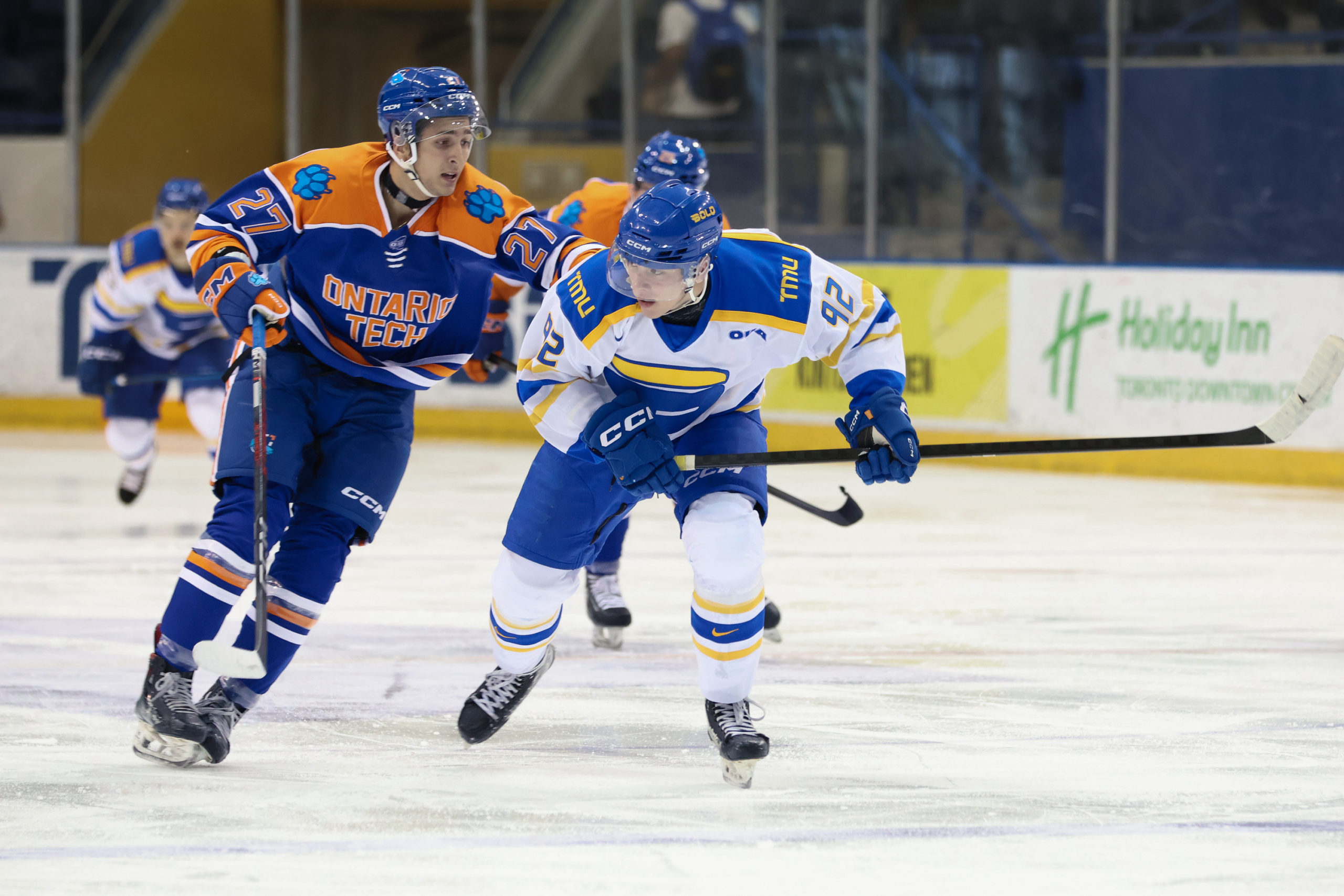 Two opposing players race across the ice