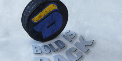 Photo illustration of a hockey puck with the bold logo on it, there is text below the puck saying "Bold is Back".