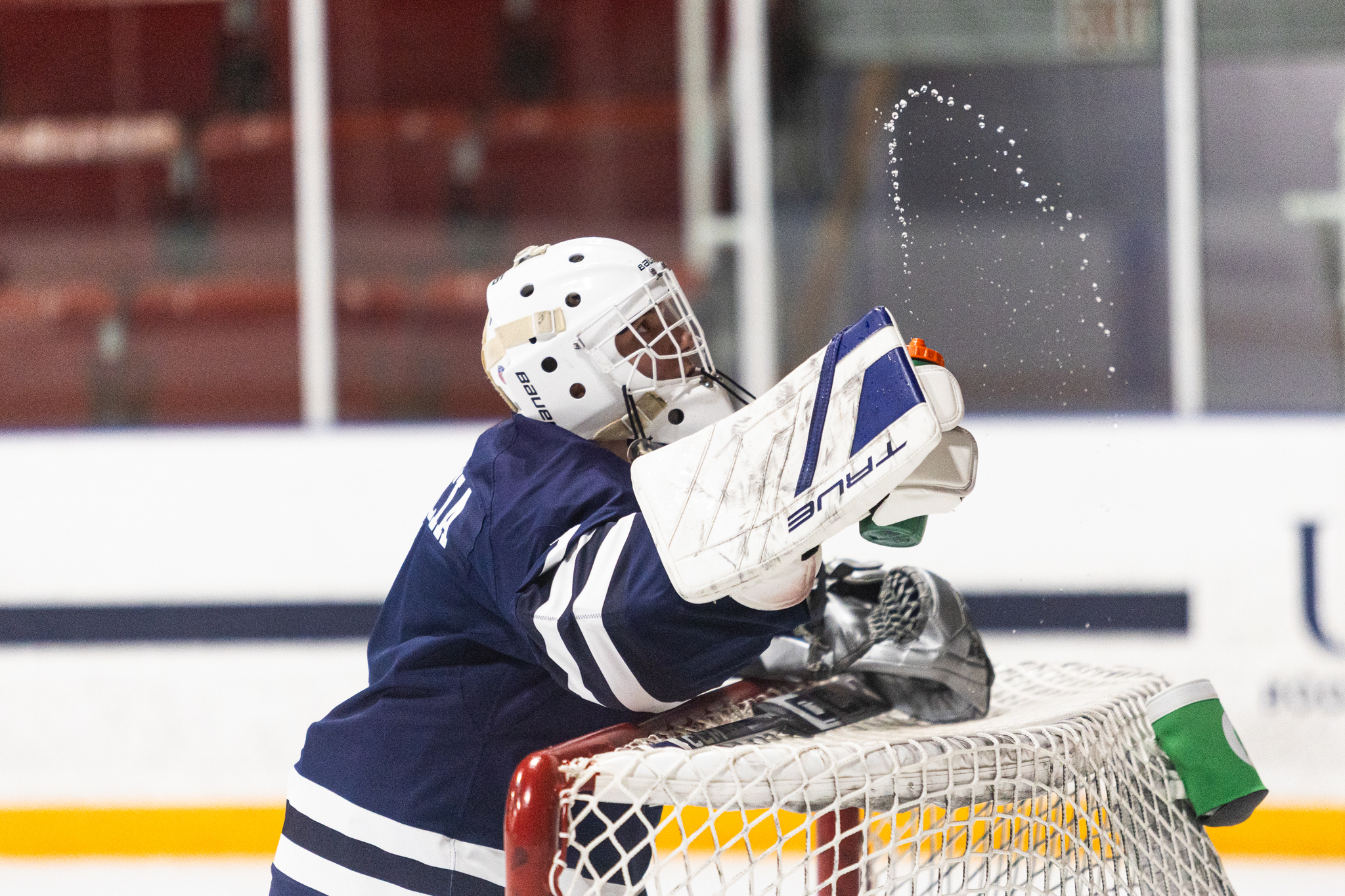 Varsity Blues goalie spraying water bottle in the air while leaning over their goal