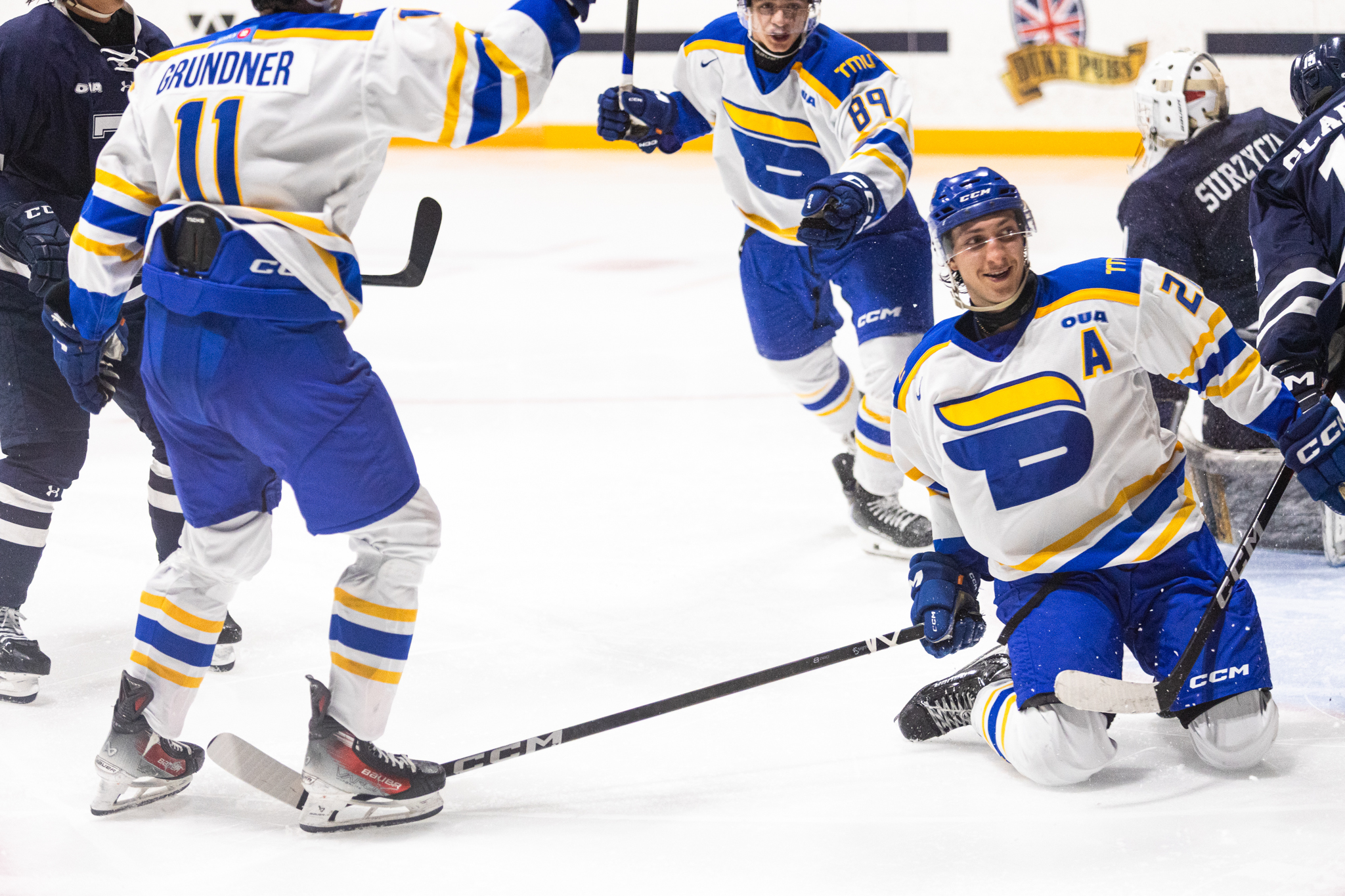 TMU bold player sliding on the ice, celebrating a goal