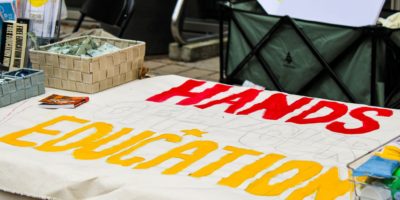 Image of a banner on a table that reads "hands of our education"