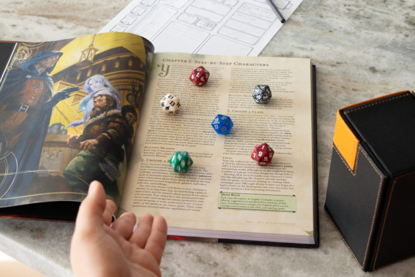Image of a book on a table with five coloured dice laid out on the book.