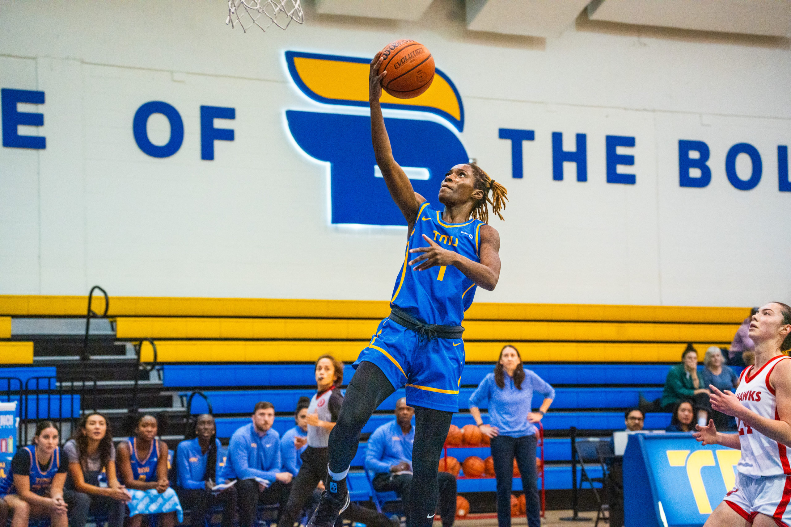 A TMU basketball player attempts a basket