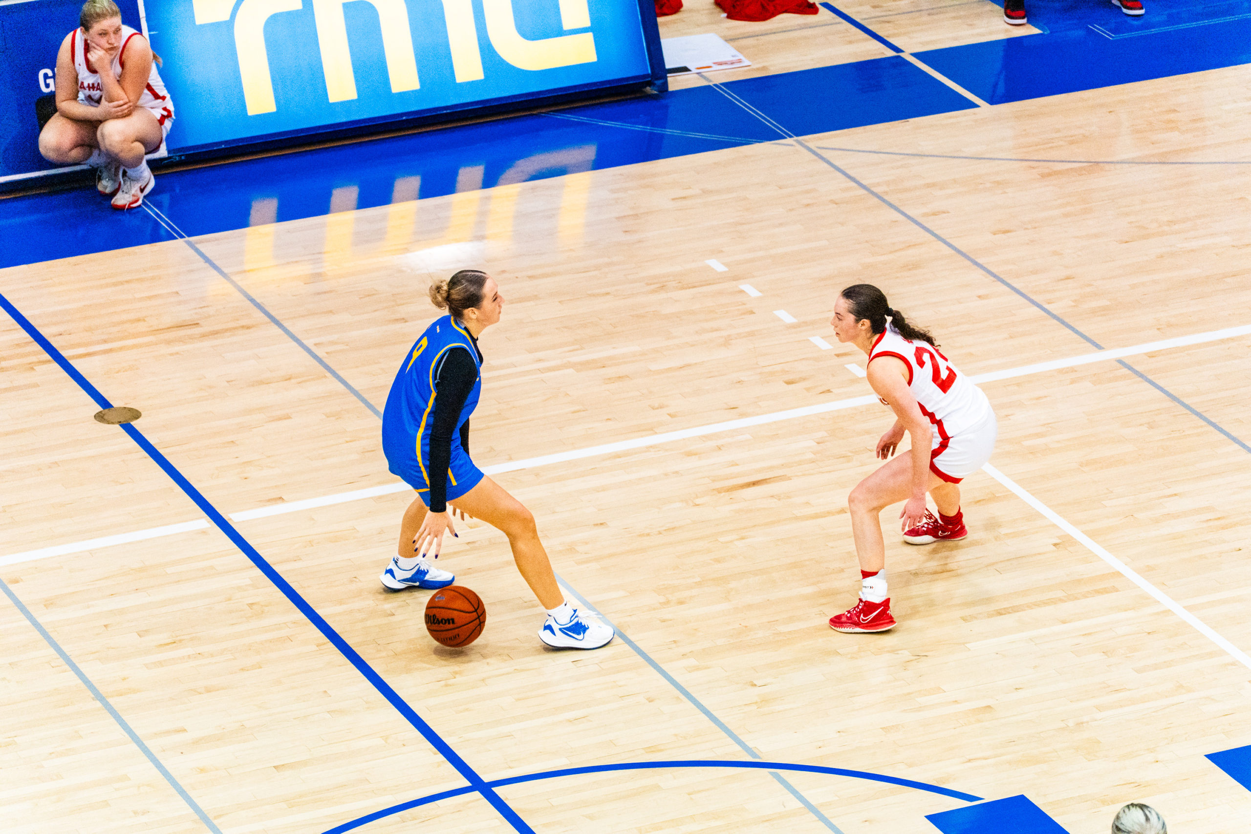 A TMU basketball player dribbles the ball as a Memorial player defends her zone