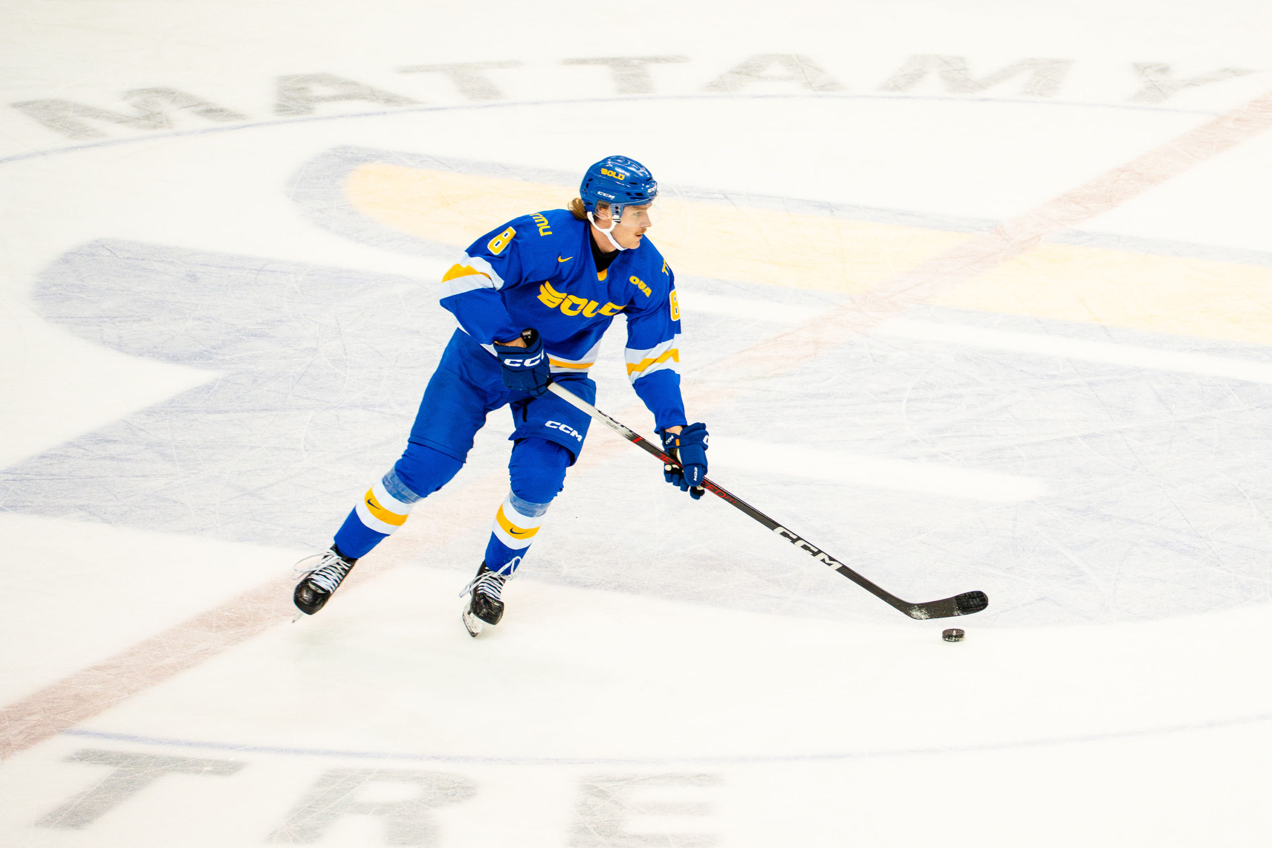 Carter MacAdams skates with the puck centre-ice