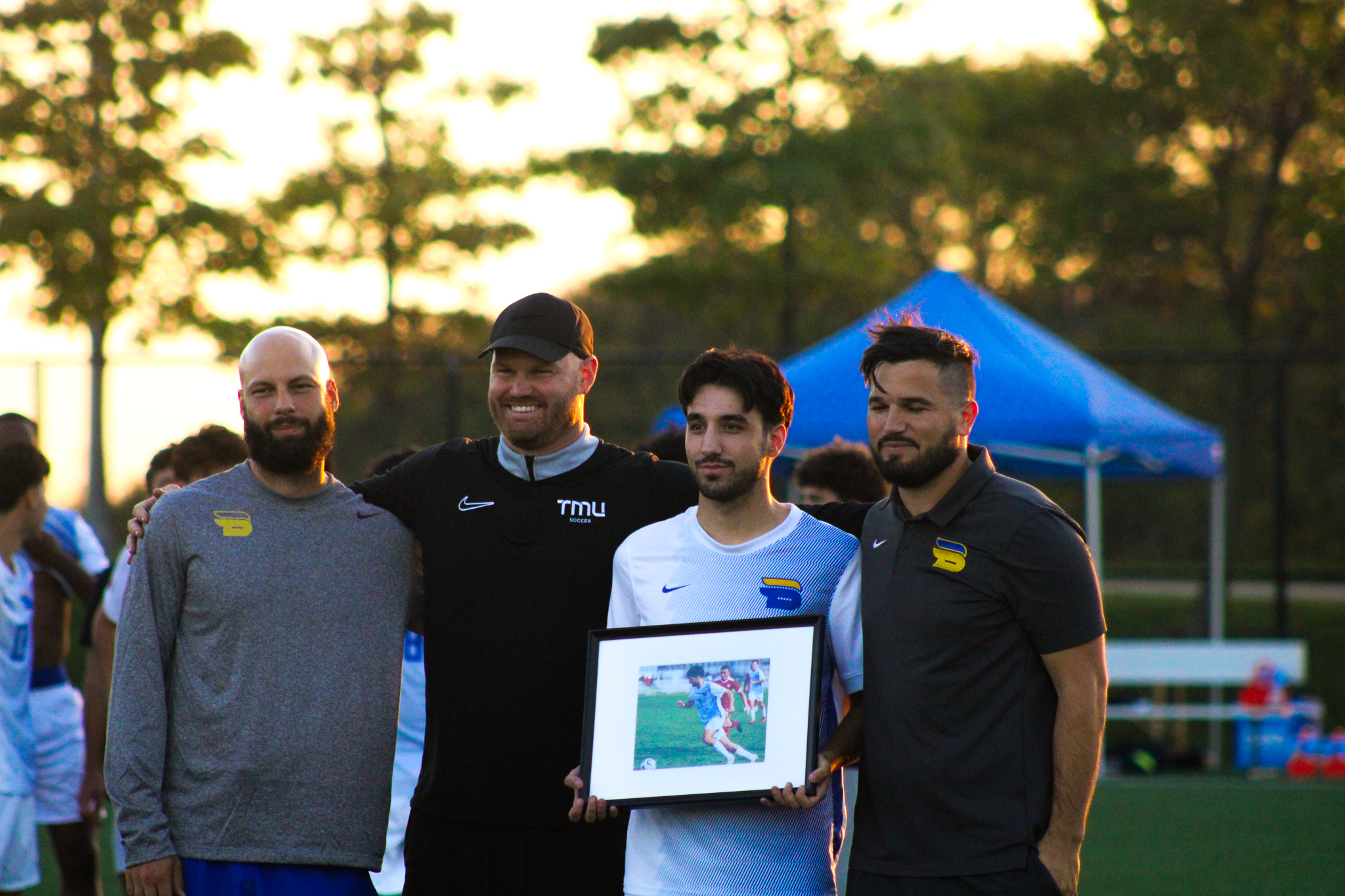 Justin Santos stands with the coaching staff on Senior Night