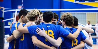 TMU men's volleyball huddle together after a play