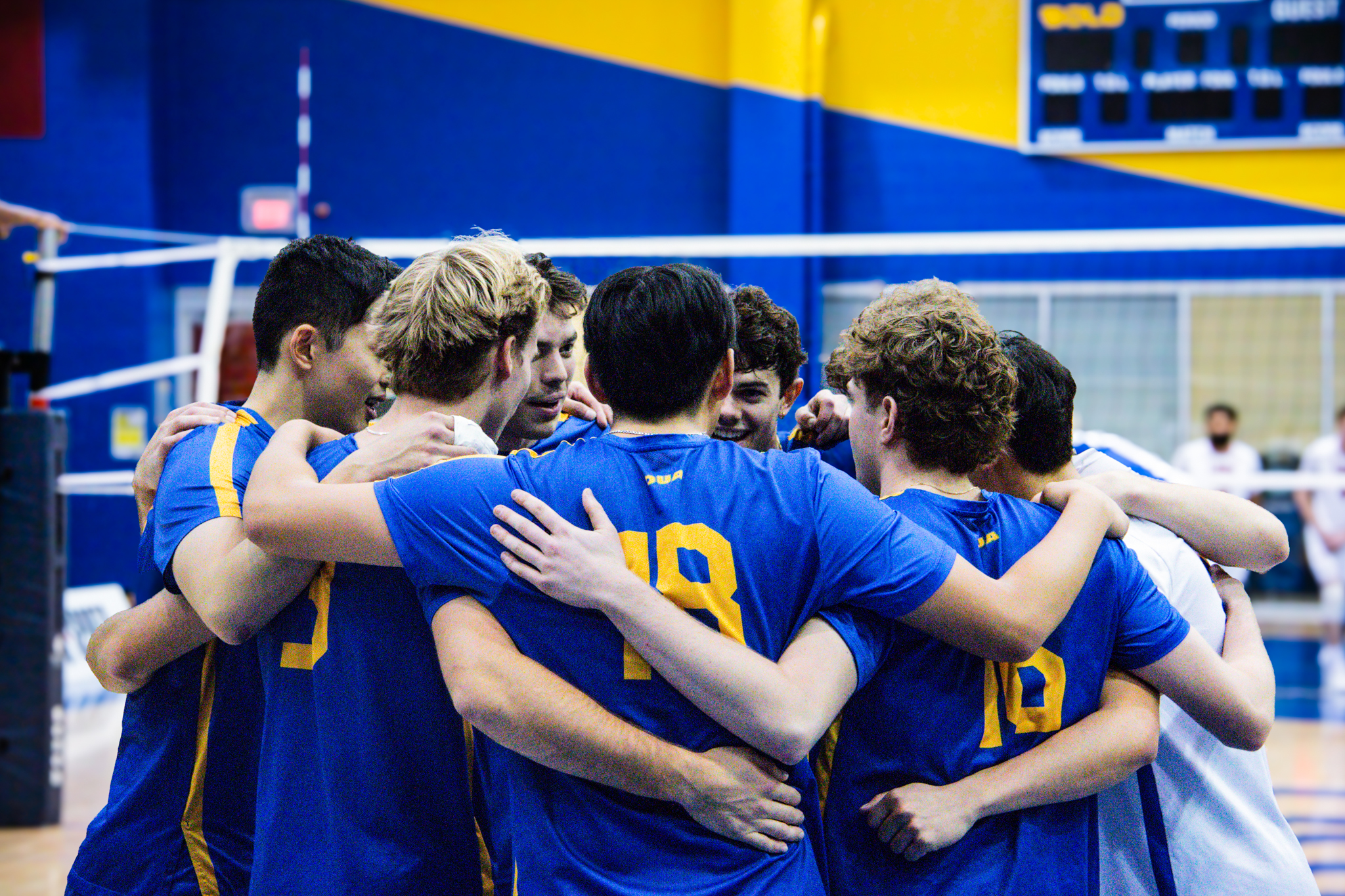 TMU men's volleyball team huddling together after match