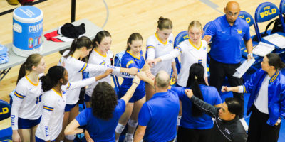 The TMU women's volleyball team puts their hands together before the game