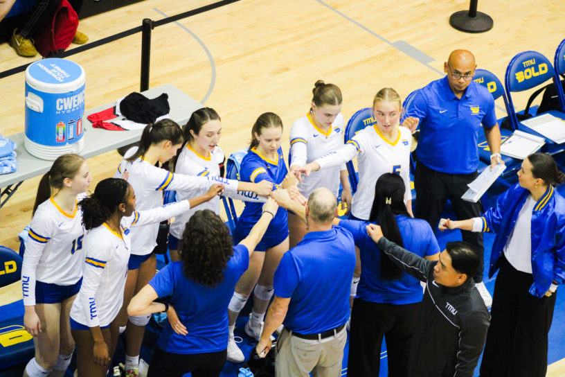 The TMU women's volleyball team puts their hands together before the game