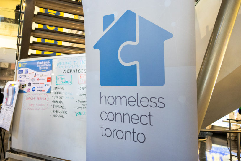 Image of a banner with a blue logo in the shape of a house and that reads "homeless connect toronto."