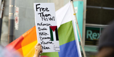 A protester holds a sign listing the names of the detained Freedom Flotilla Coalition members.