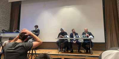 Image of three people sitting on a stage talking to a crowd.