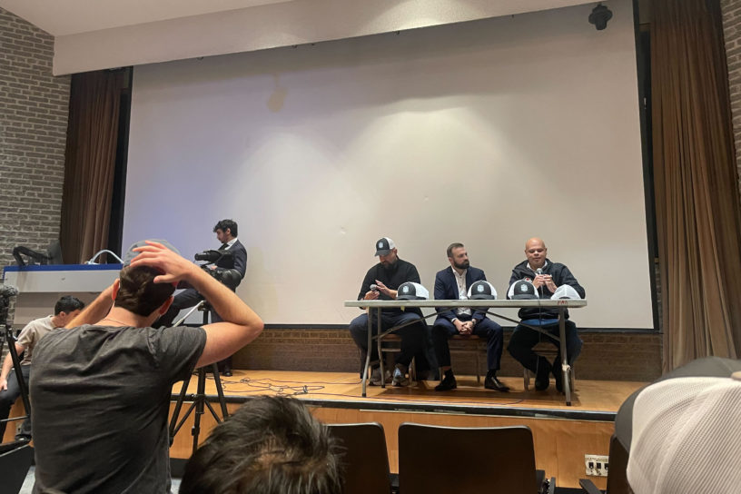 Image of three people sitting on a stage talking to a crowd.