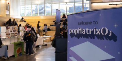 Image of the interior of the SLC lobby with booths set up and a sign that reads "welcome to popMatrix."