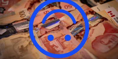 Image of fifty and one-hundred dollar bills laid out with an illustration of a blue upside-down smiley face on top.