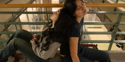 Image of two people leaning against each other sleeping on a bench.