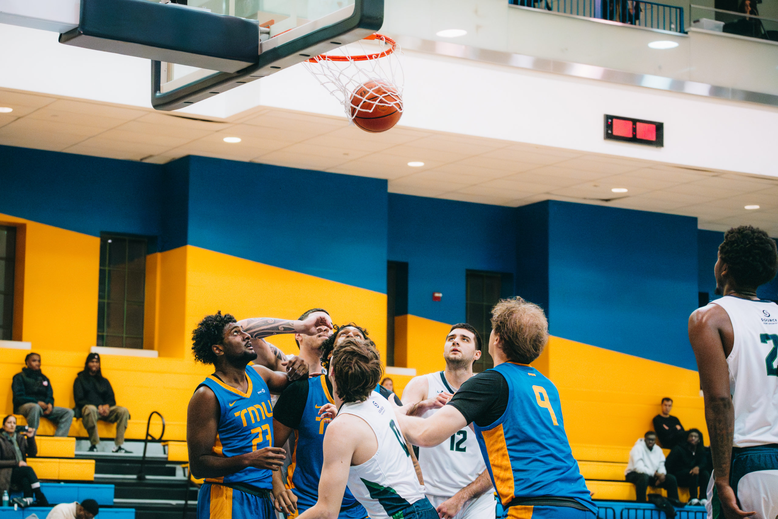 TMU Bold men's basketball team boxing out Nipissing players for a rebound