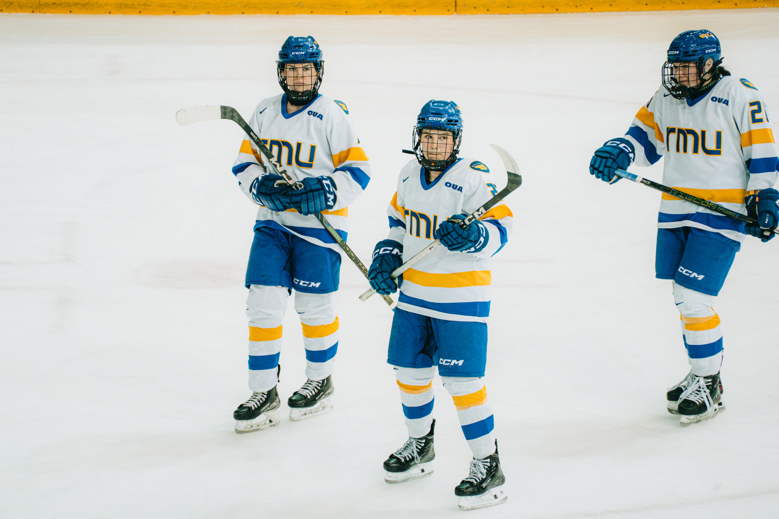 Three TMU women's hockey players skating during a stoppage of play at the Mattamy Athletics Centre