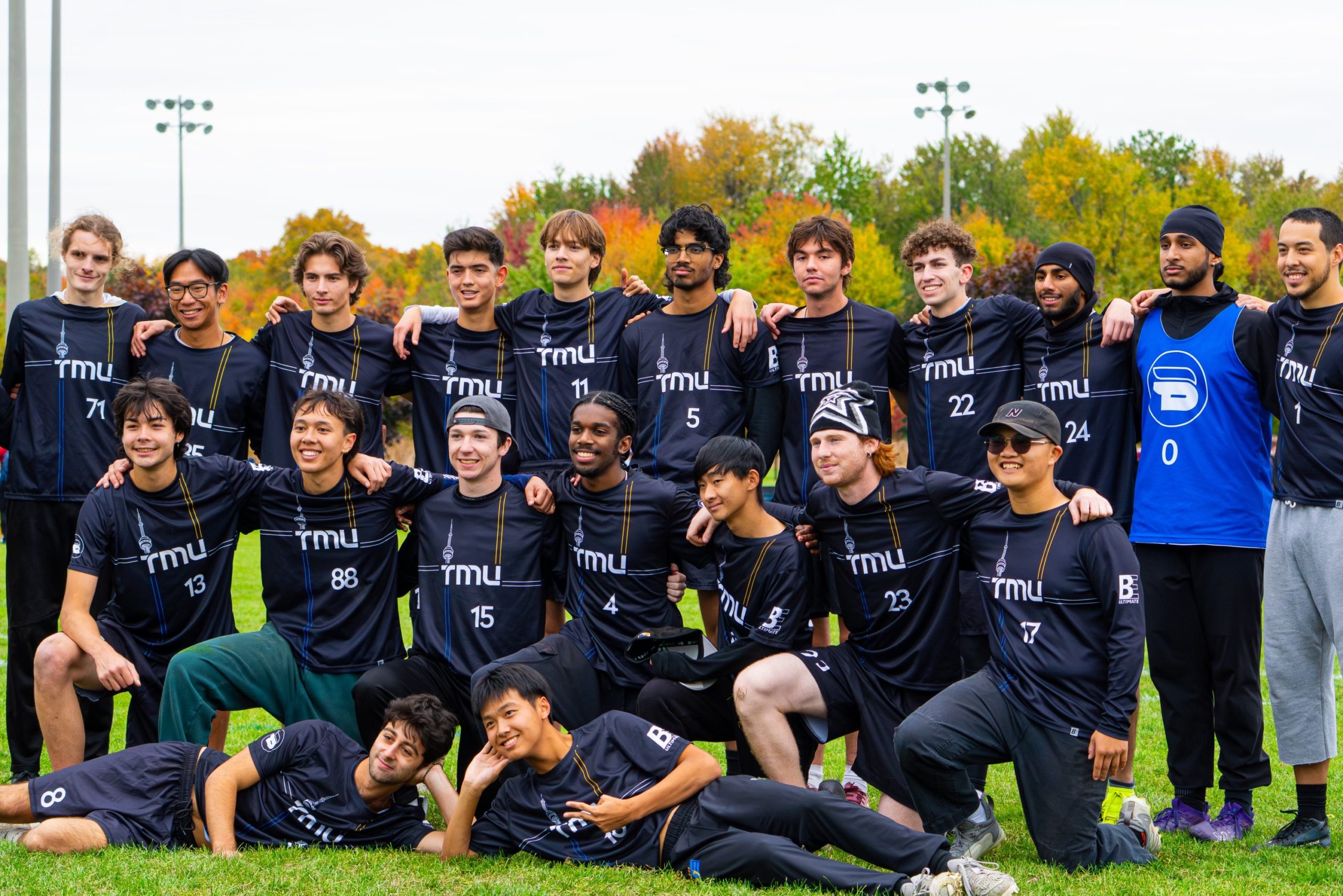 The men's frisbee team stands shoulder to shoulder on the field
