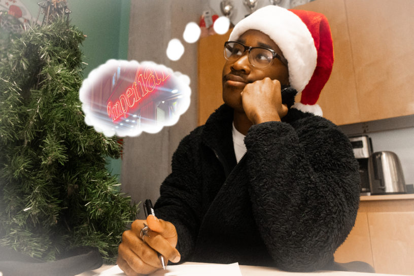 Image of a person sitting at a desk writing on a piece of paper with a though bubble illustrated around them. The thought bubble has a photo with a sign that reds "Imperial."