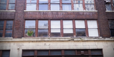 Image of a building with the grinch peeking out of a window from the bottom left side of the frame.