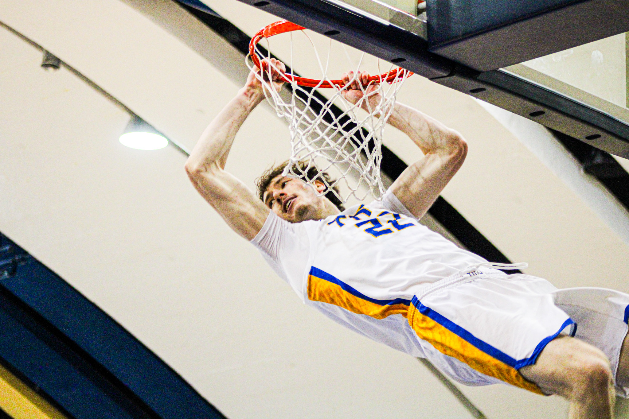 Aidan Wilson hanging onto the rim after a dunk