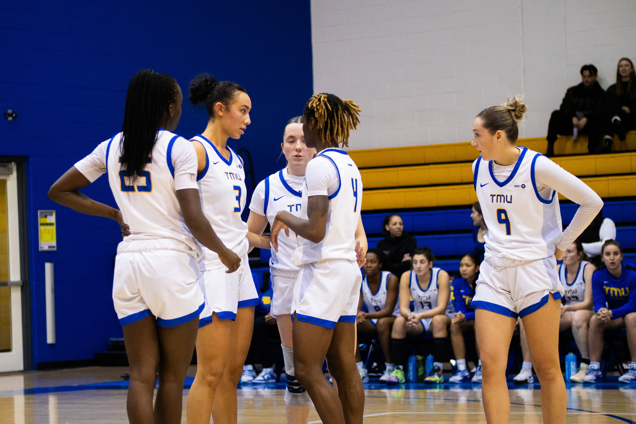 TMU women's basketball team gathered on the court during a stoppage of play at the Mattamy Athletics Centre