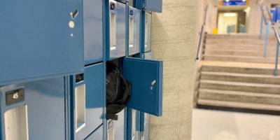 Image of a row of small blue lockers with one open that has a bag sticking out.