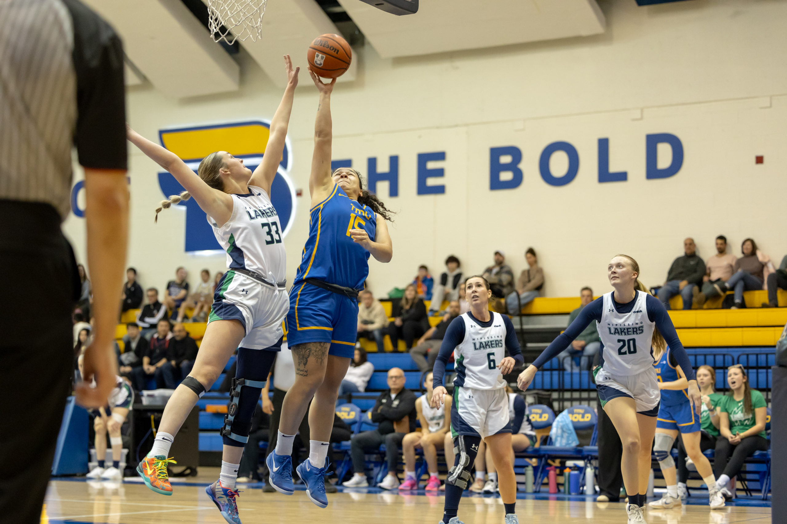 A TMU player reaches for the basket amidst Nipissing defense