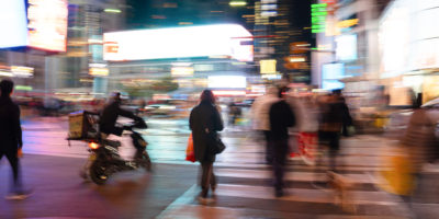 Blurry image of people crossing the street at the Yonge and Dundas intersection.