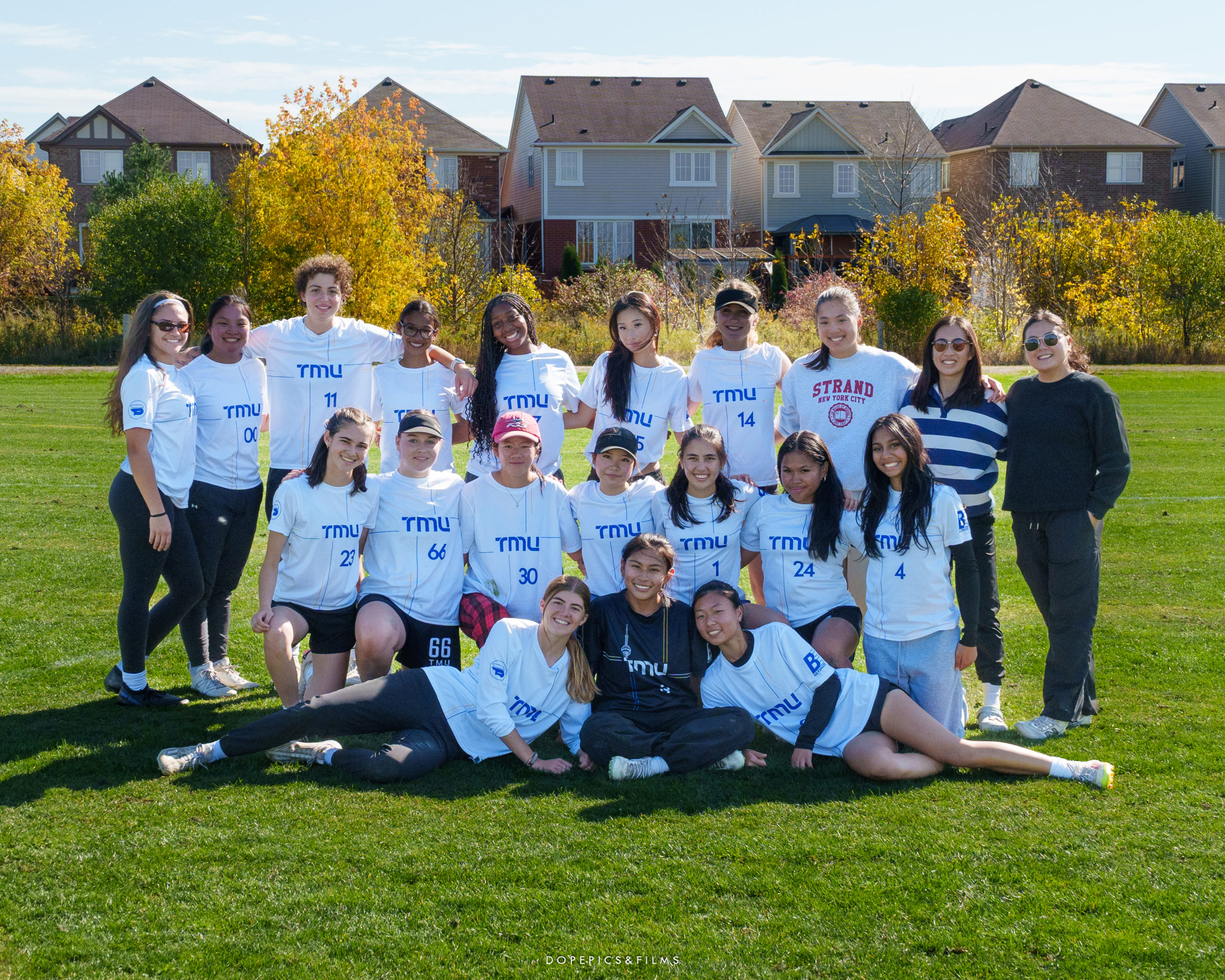 The women's frisbee team stands shoulder to shoulder on the field