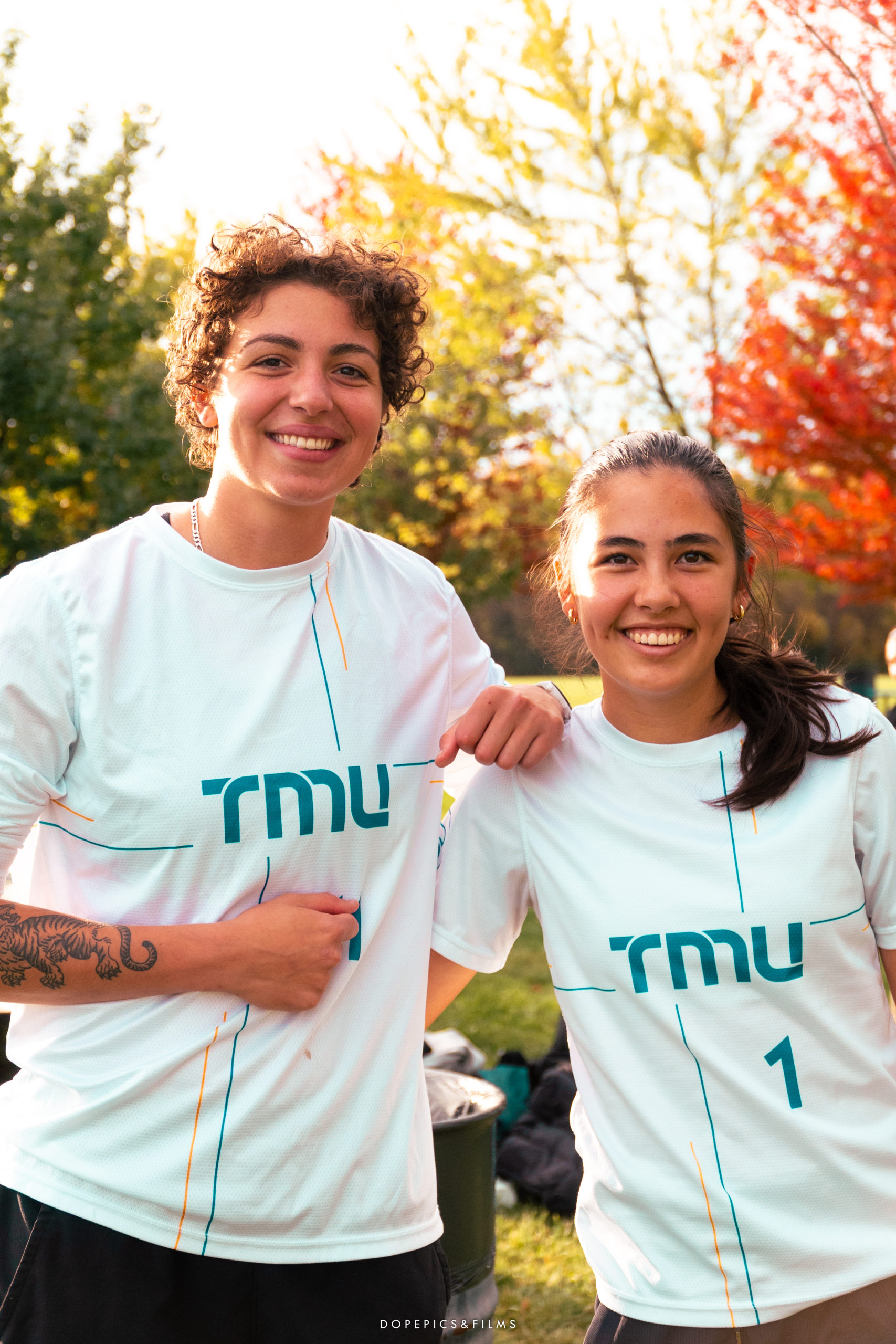 Two women's frisbee players stand together and smile